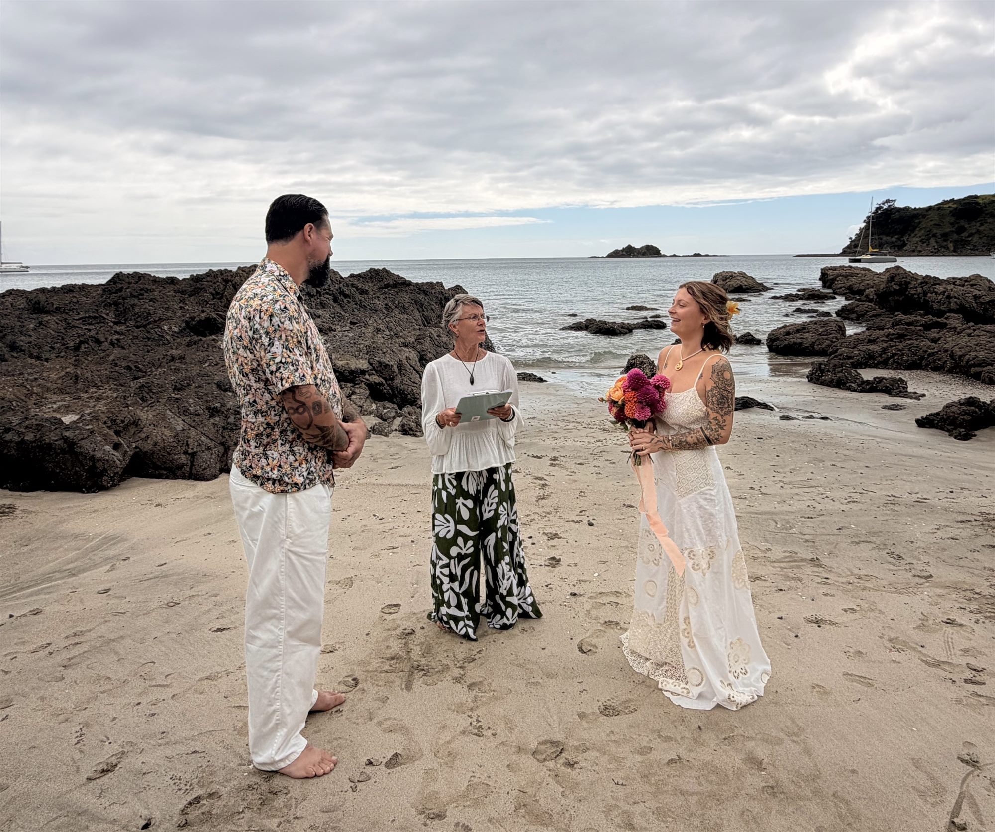 Barefoot beach wedding ceremony on Waiheke Island with rocky coastline