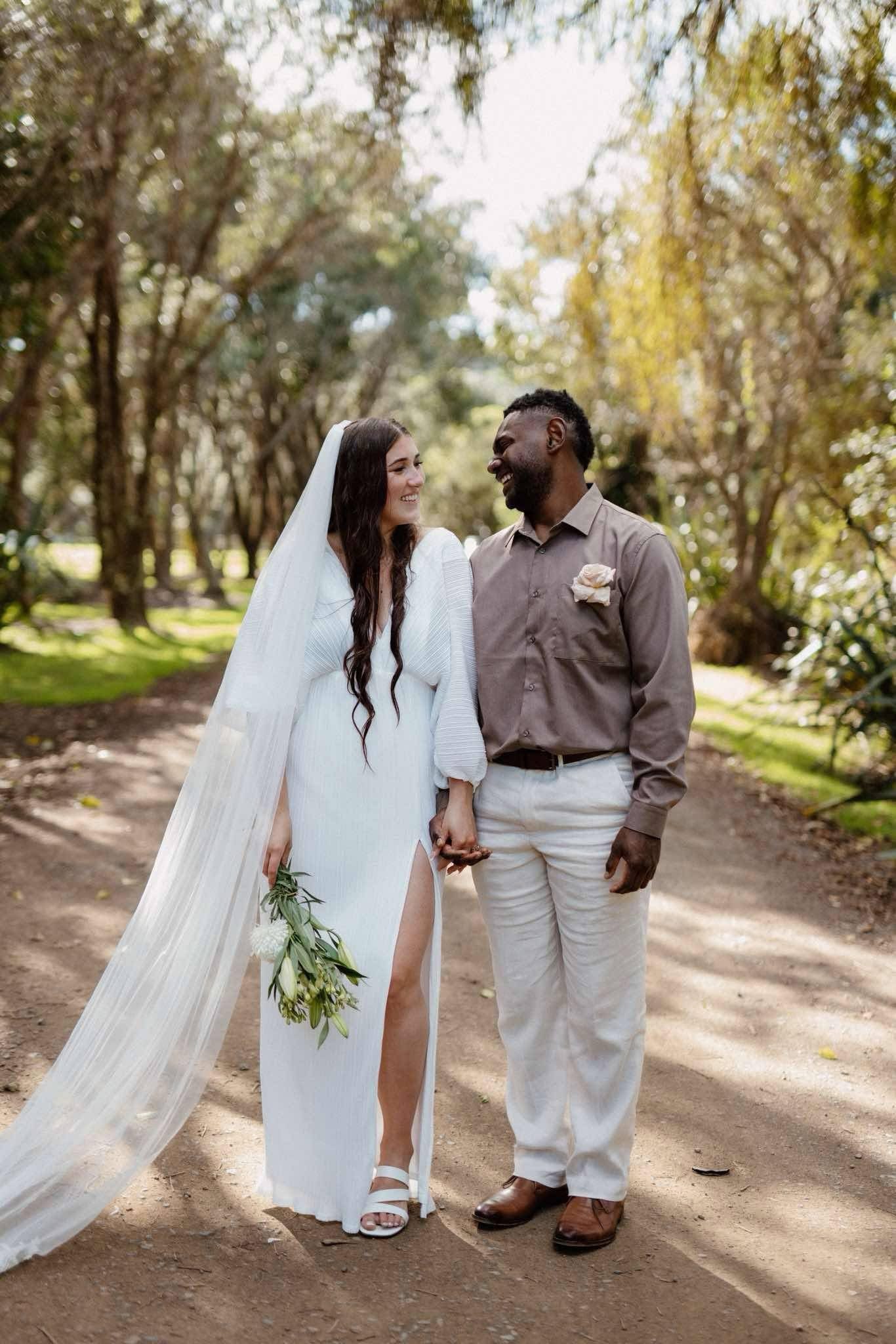 Chloe and Brandon walking hand in hand through a beautiful garden on their Waiheke Island wedding day