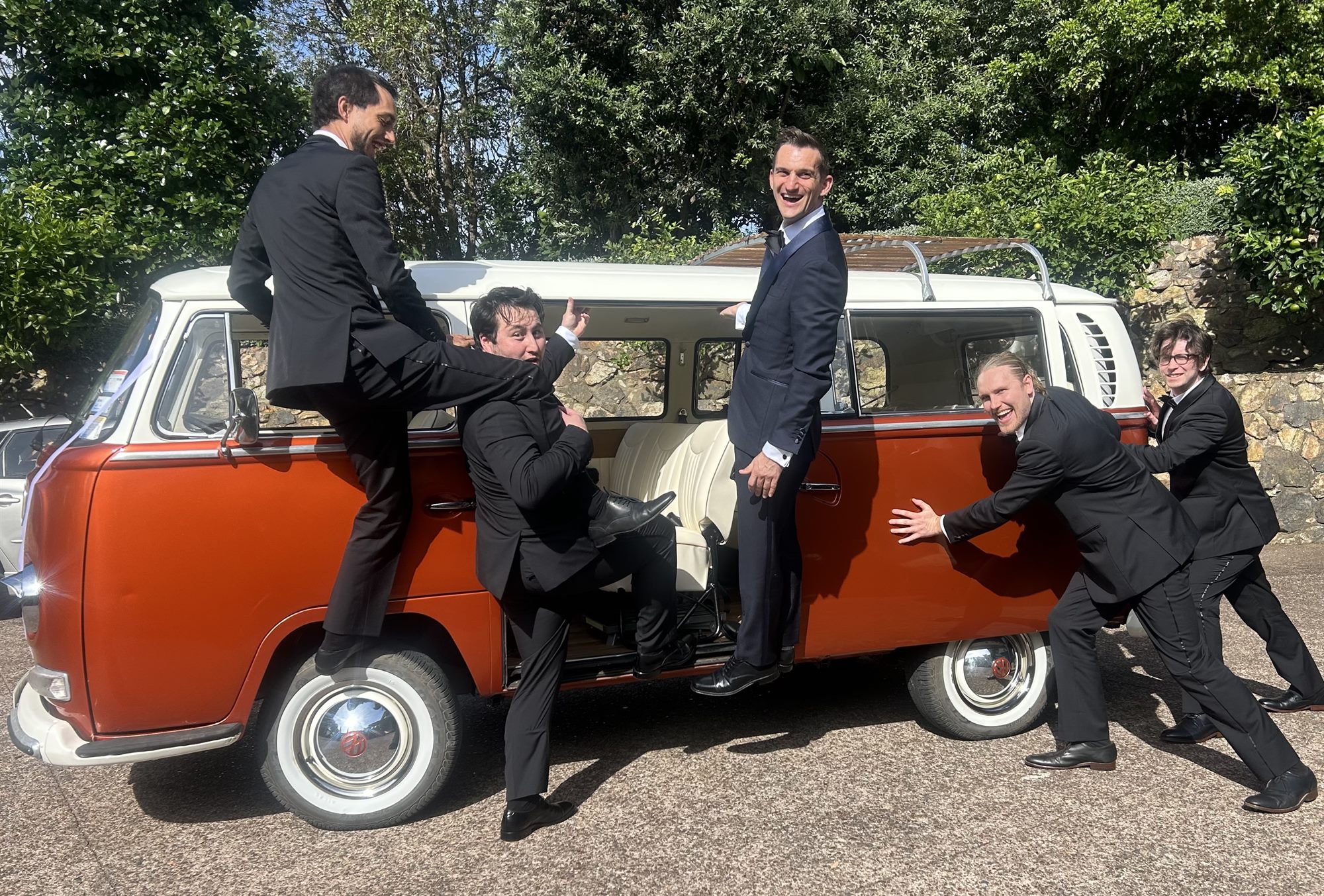Groomsmen playfully posing with Solana the 1969 Kombi van at a Waiheke Island wedding