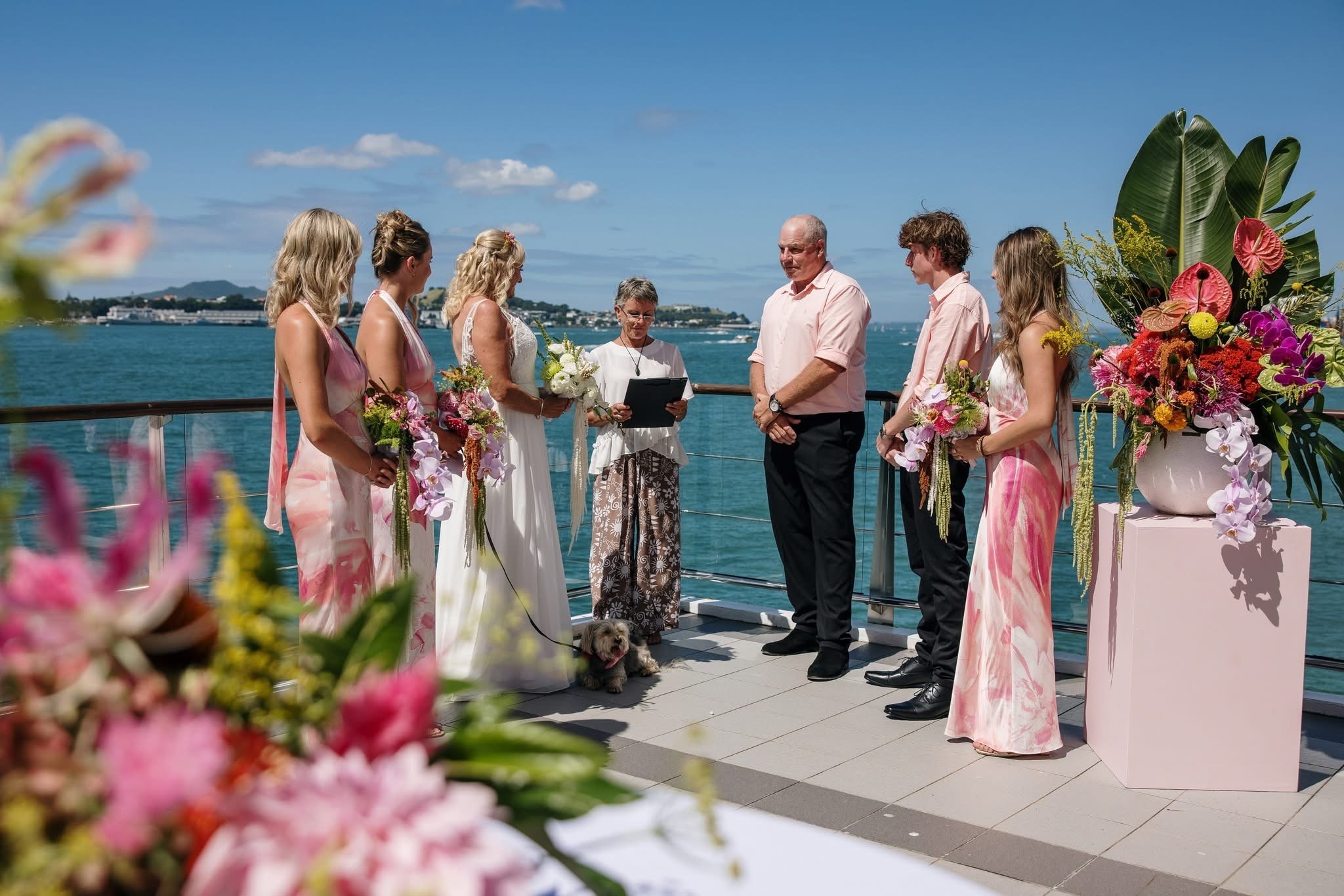 Sue and Pablo's waterfront wedding ceremony on Waiheke Island - bridal party, tropical flowers and harbour views