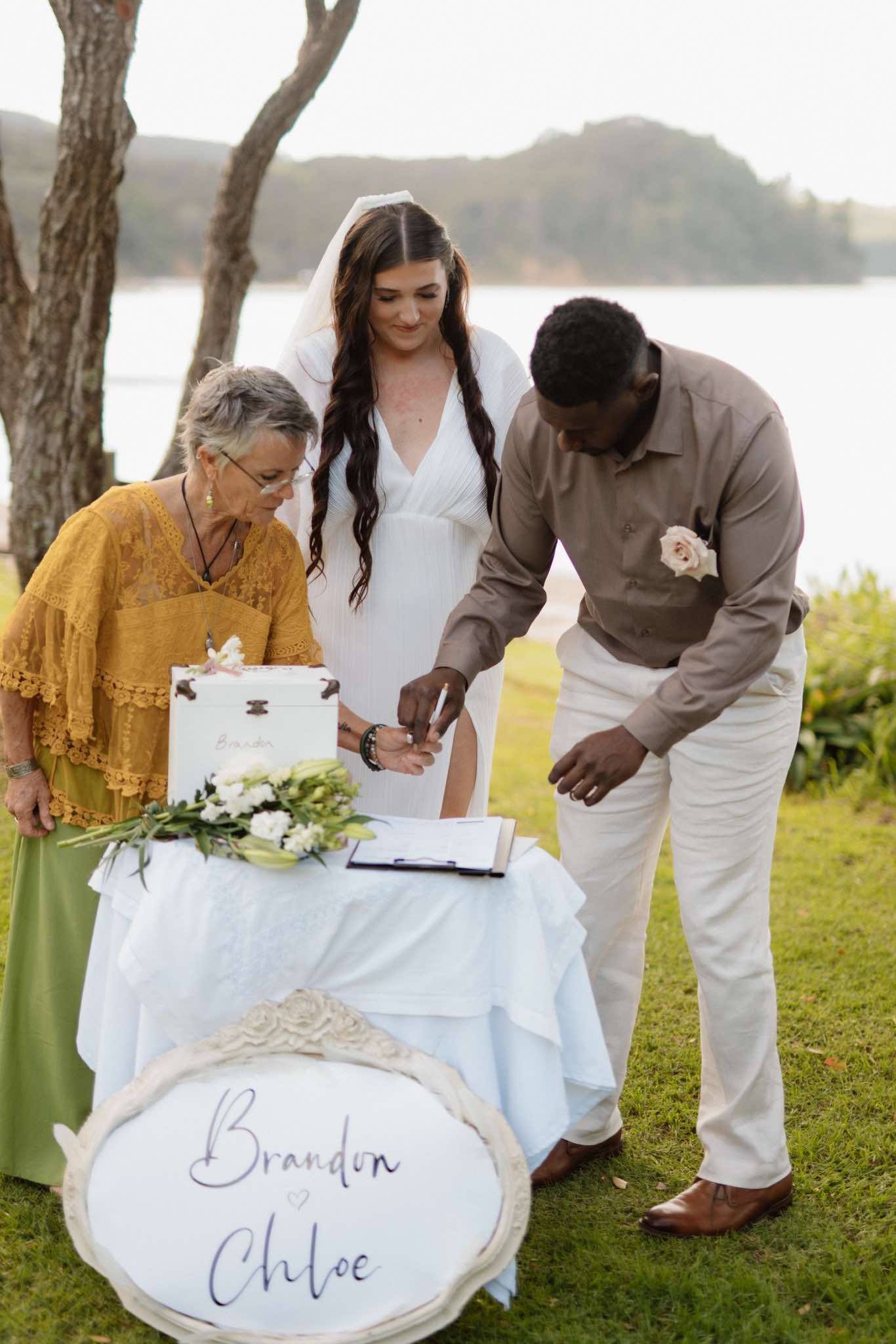 Couple signing the marriage register at their Waiheke Island garden ceremony - officiated by Linda Deverell